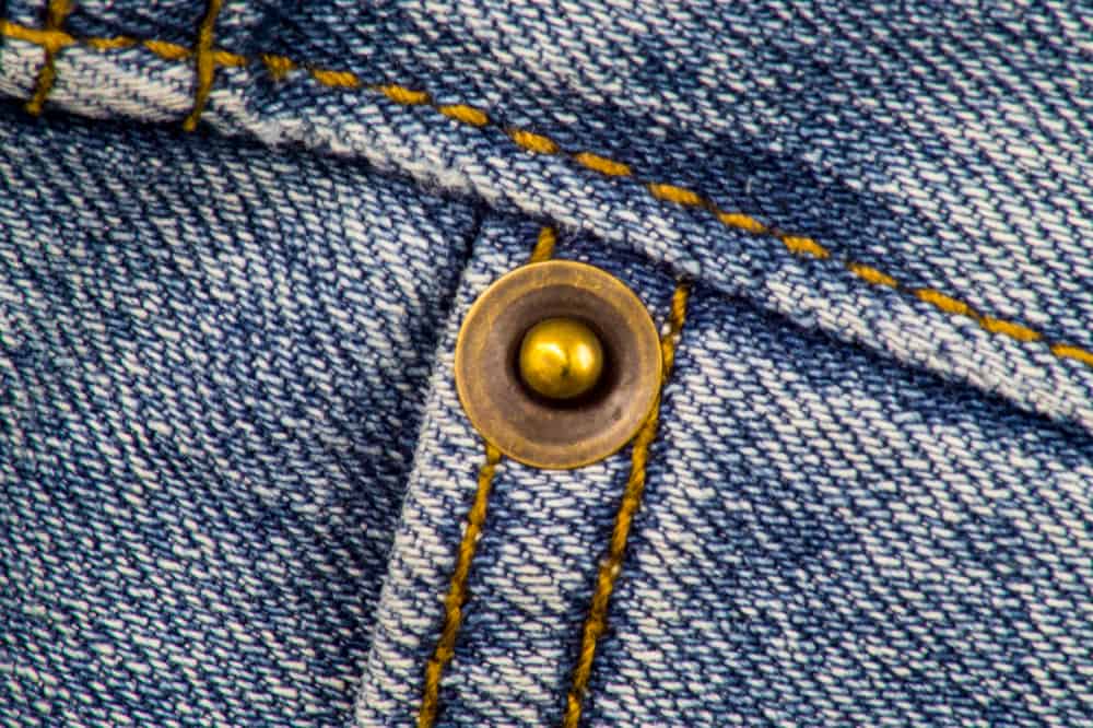Close-up of denim jeans with rivet and stitching.