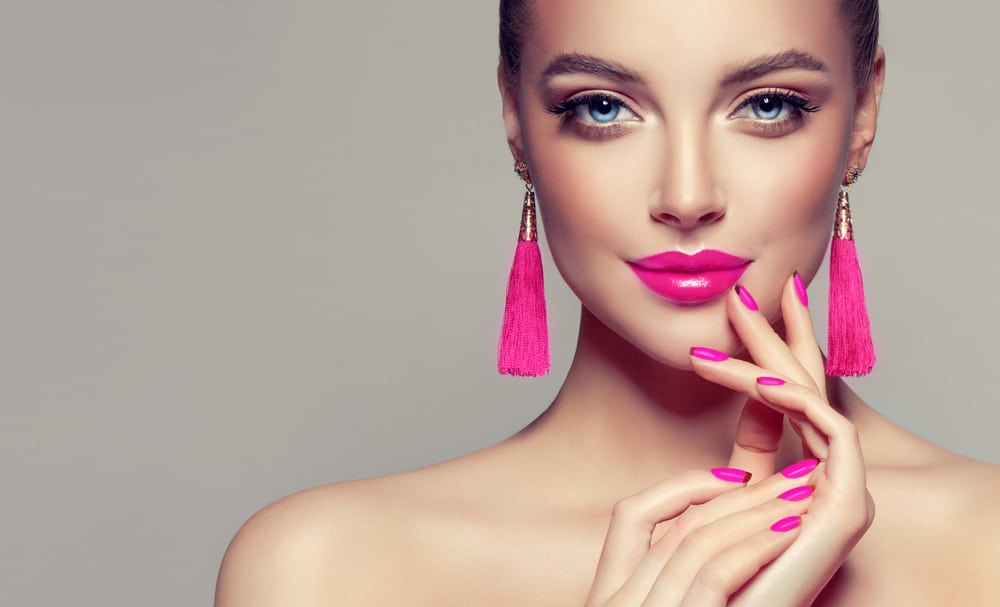 Model with pink lipstick, matching manicure, and tassel earrings.