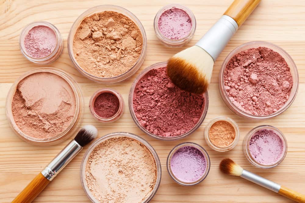 Mineral makeup cosmetics and brushes on a wooden table.