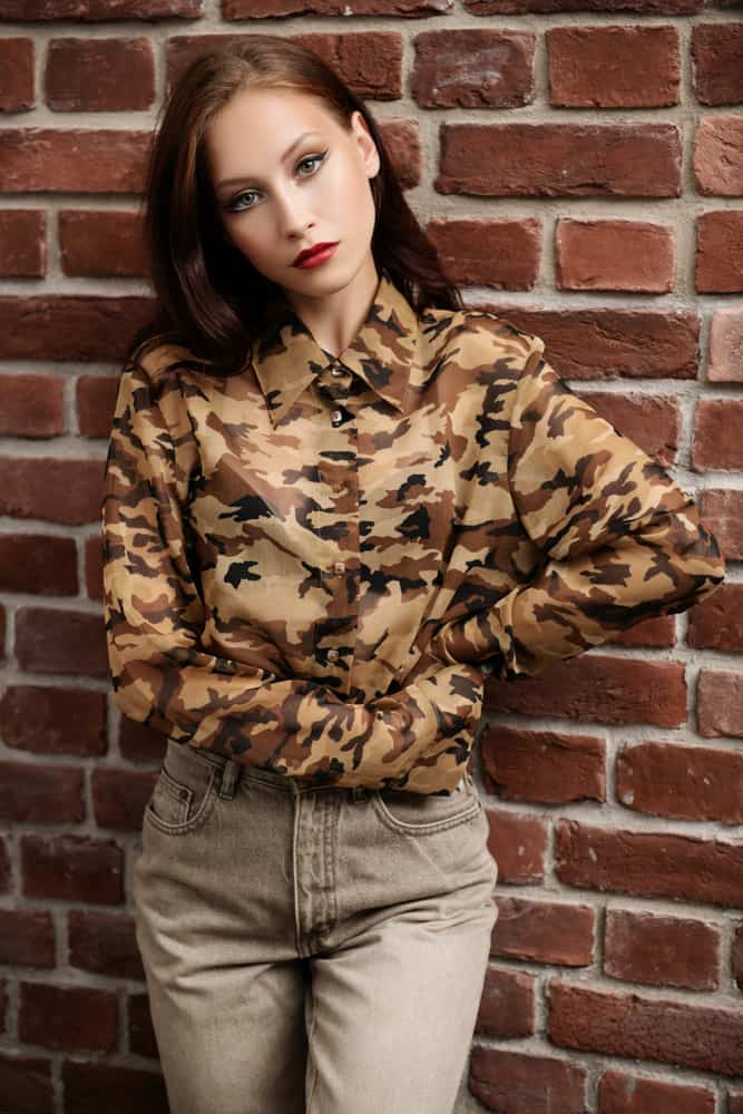This is a close look at a woman wearing a button-down blouse with camouflage patterns.