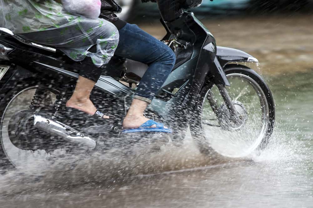 This is a couple on a motorcycle riding through the flooded street.