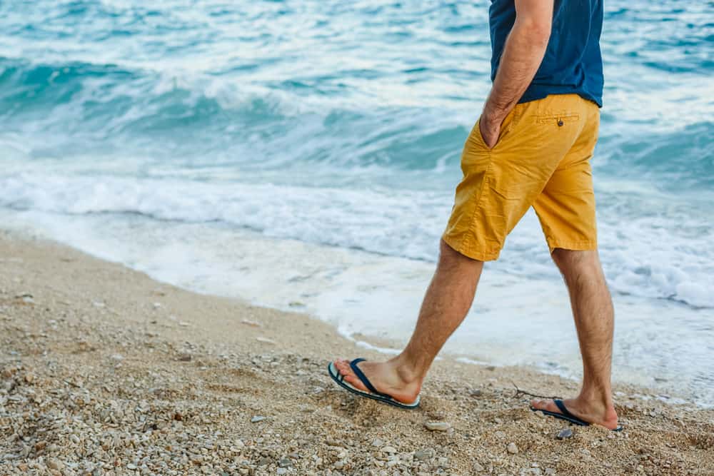 A close look at a man wearing a pair of shorts while walking on the beach.