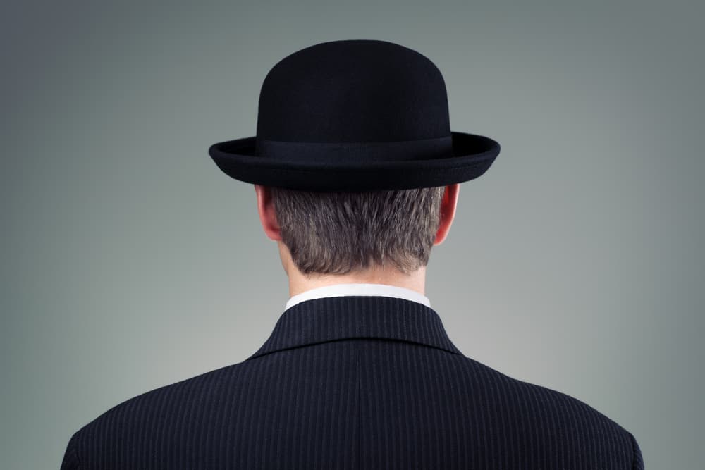 A back view of a man wearing a dark suit and a bowler hat.
