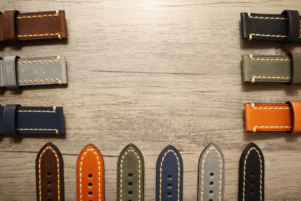 This is a close look at various colorful watch straps on a wooden table.