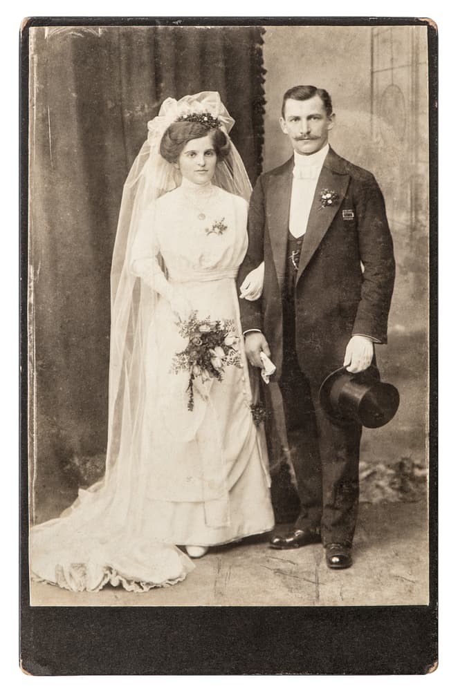 Antique portrait of a married couple in white wedding dress and black suit.