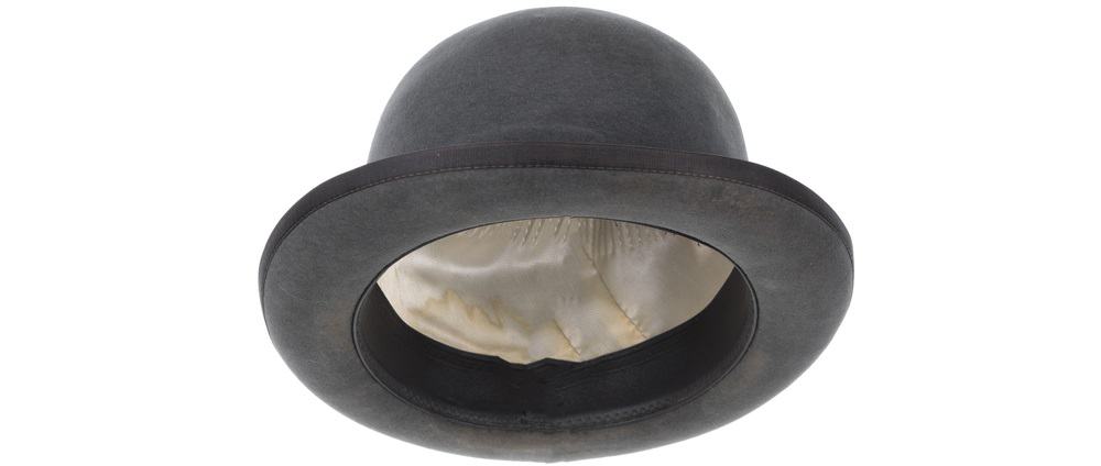 A close look at a charcoal gray bowler hat with silk lining inside.