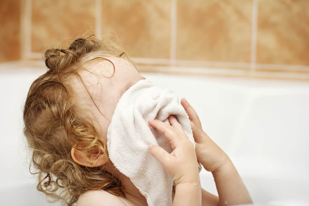 This is a kid using a washcloth in the bathtub.