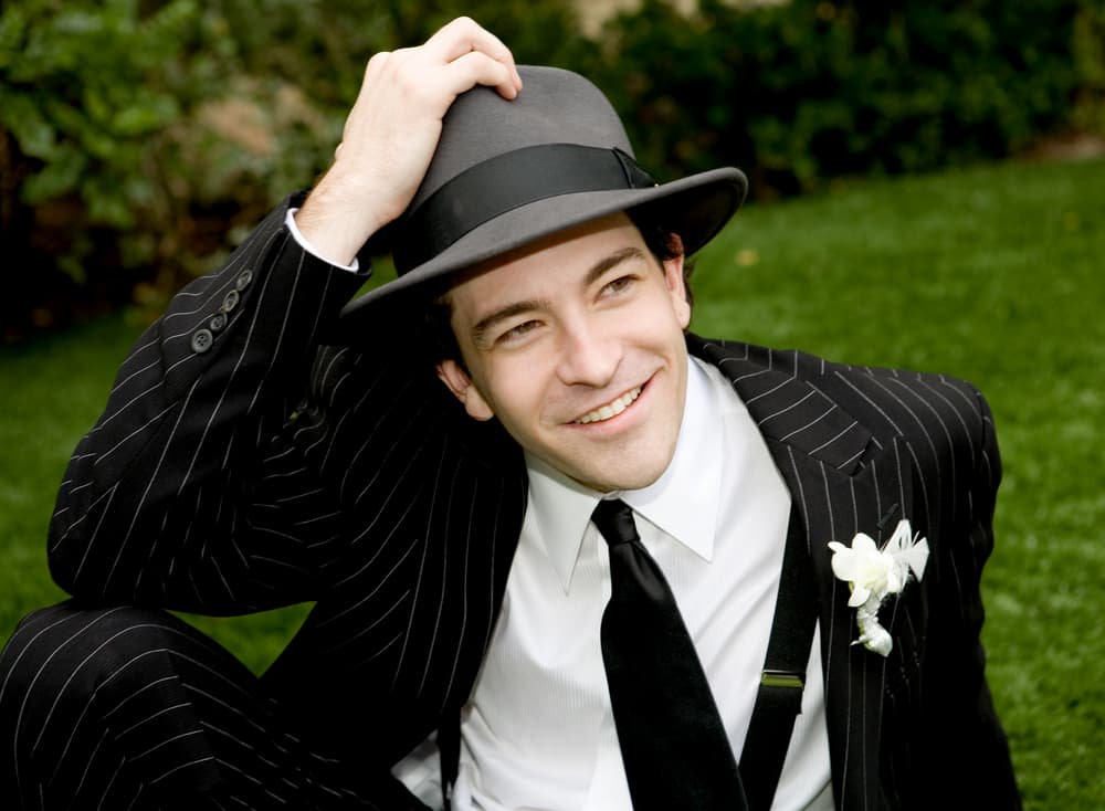 A man wearing a pin-striped suit with his fedora.