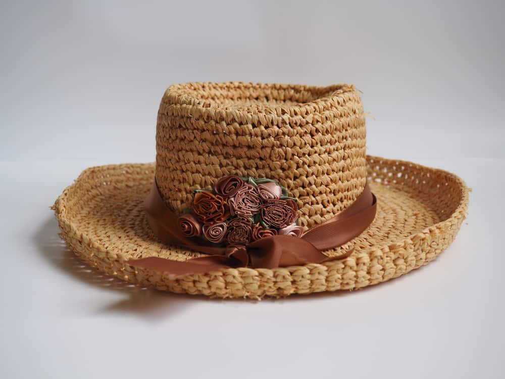 Chupalla hat adorned with brown ribbon and flowers.