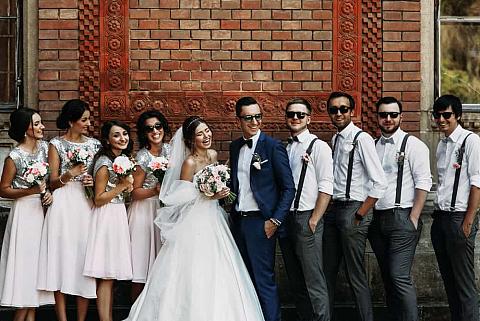 The bride and groom with their groomsmen wearing suspenders and bridesmaids wearing skirts.