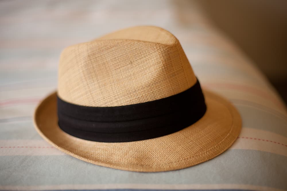 This is a woven straw hat fedora with black band.