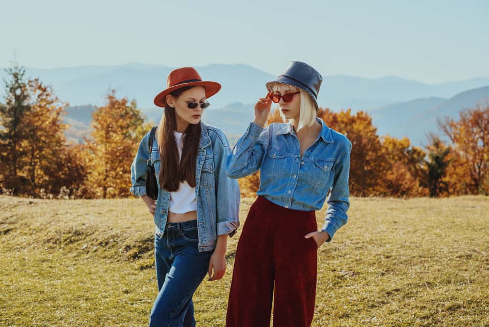 These are two women wearing a fedora and a bucket hat with their denim jackets.