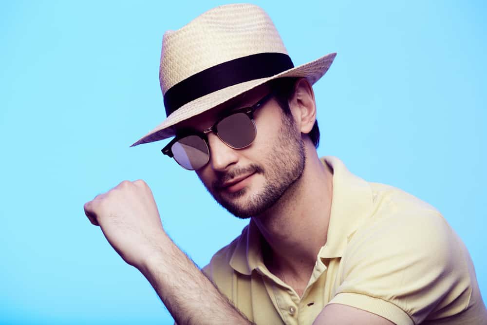 A man wearing yellow polo shirt and a fedora.