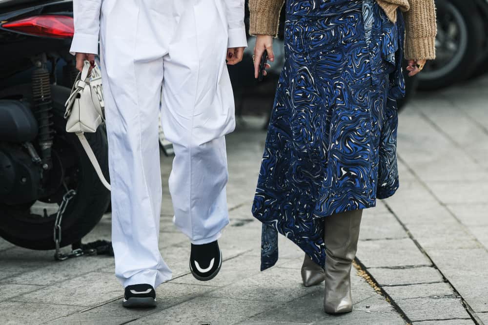 A close look at a woman wearing a blue patterned maxi skirt with her gray leather boots.