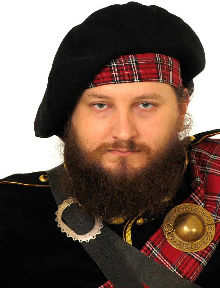 This is a man wearing a vintage Scottish warrior costume topped with a bonnet.