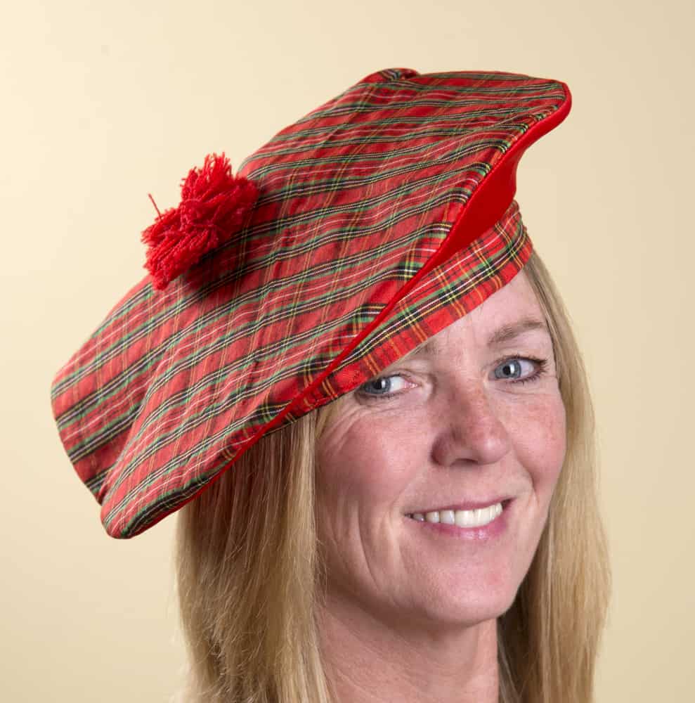 This is a close look at a woman wearing a red patterned Scottish tam o’shanter.