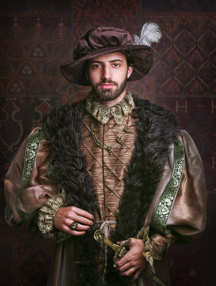 This is a man wearing a vintage 16th Century costume topped with a feathered historical bonnet.