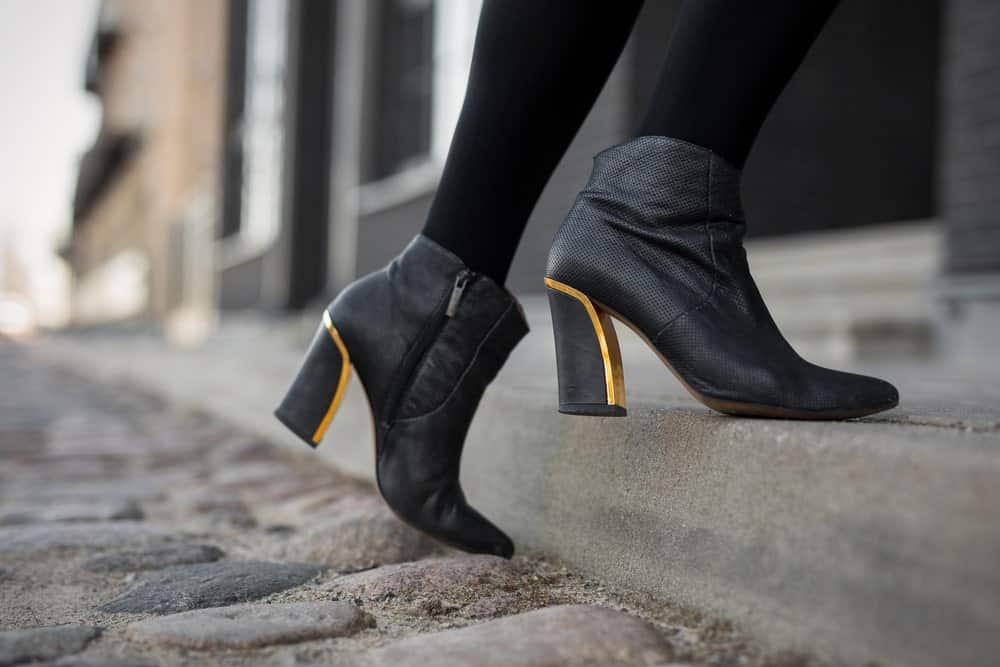 Woman in ankle boots climbing a stoop.