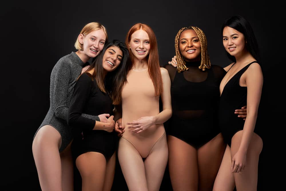 Women wearing bodysuits against the black background.