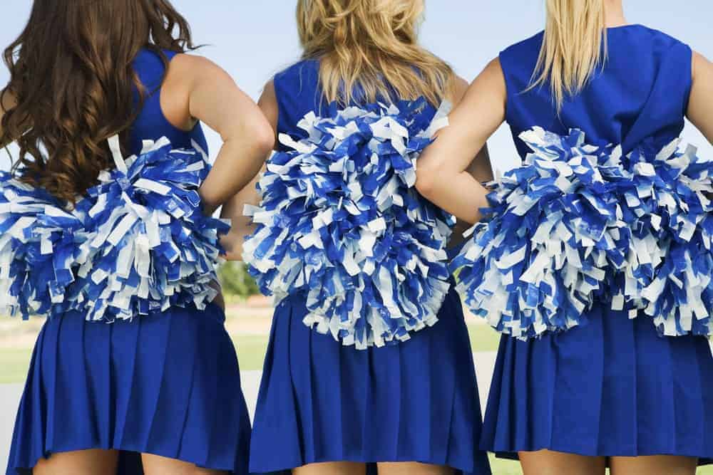 Back view of three cheerleaders holding pom poms.