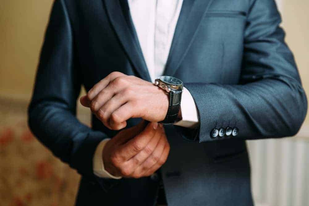 Cropped photo of a man in suit wearing a luxury wristwatch.