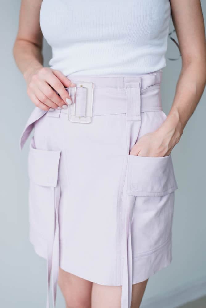 Woman wearing a white blouse and lilac cargo skirt.