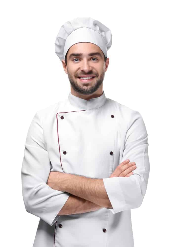 A chef folds his hands and smiles at the camera.