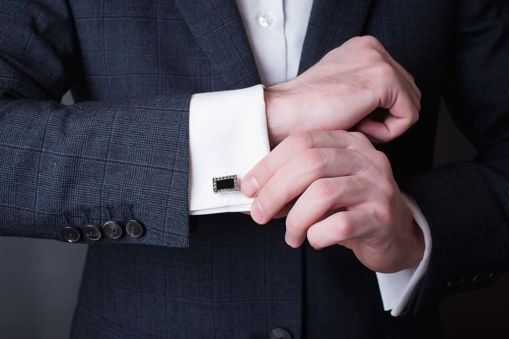 Man in a tux fixing his cufflink.