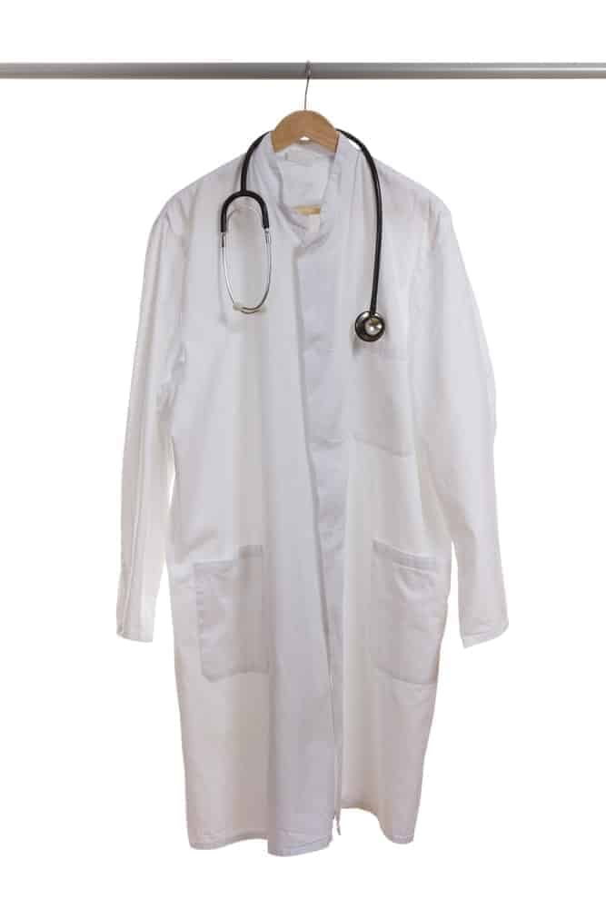A doctor's coat with a stethoscope hangs on a hanger.