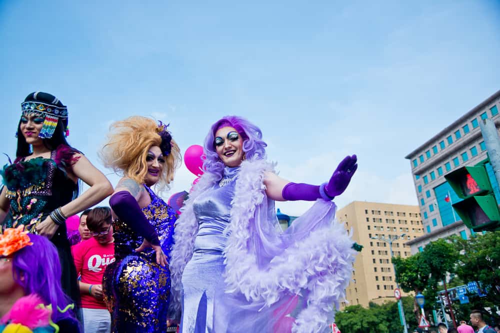Drag queens wearing colorful dresses during an event.
