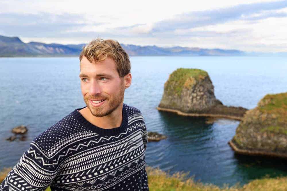 Man in a fair isle sweater on a picturesque landscape.