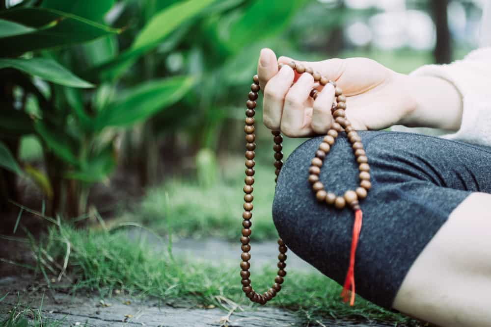 Close-up of female hand meditating and holding rosary.