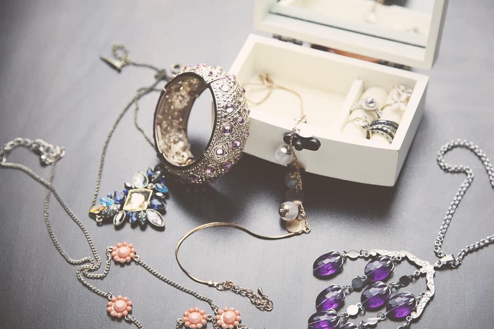 A collection of vintage jewelry in white jewelry box.