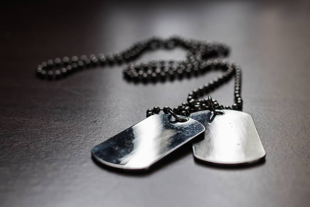 A couple of military dog tags on dark wood table.