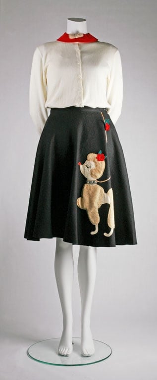 Mannequin dressed in a long sleeve blouse and black poodle skirt.