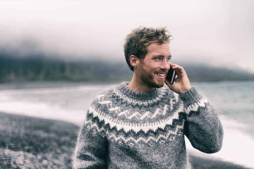Man in a pullover sweater talking on phone.