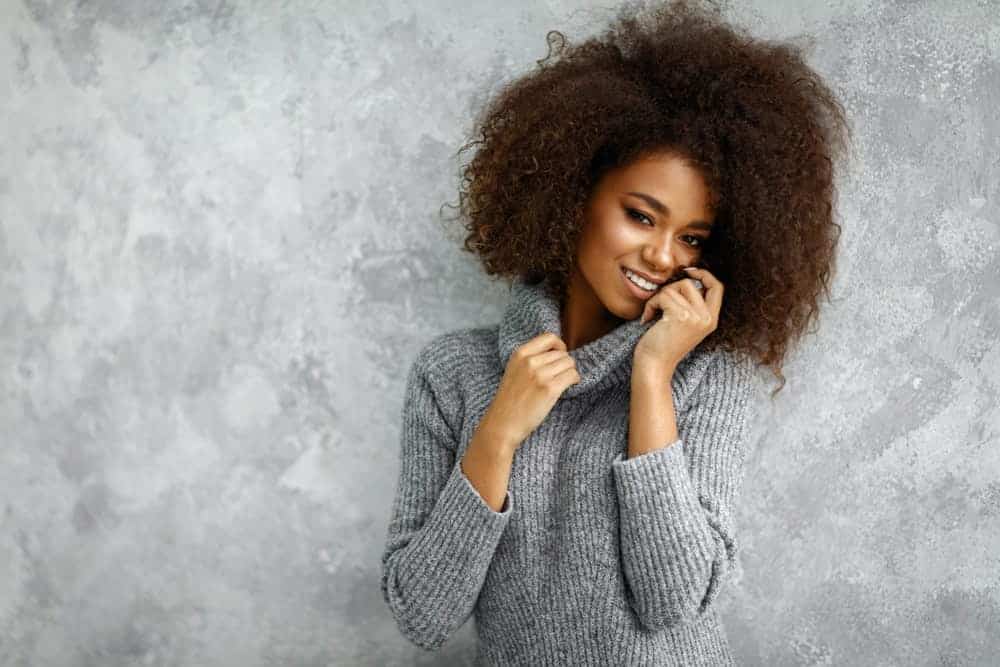 Woman with afro hairstyle wearing a ribbed sweater.