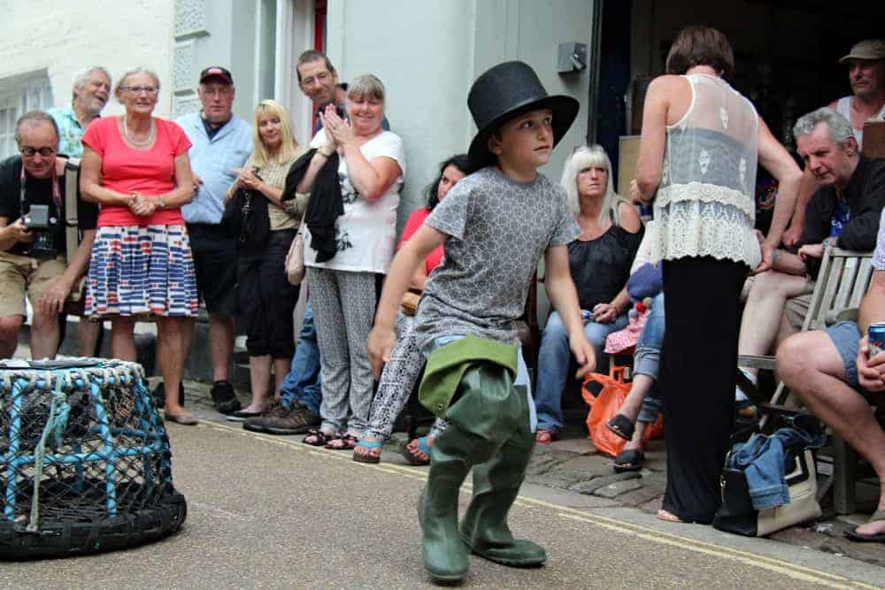 A boy in Courthouse Street wearing a top hat and sea boots.