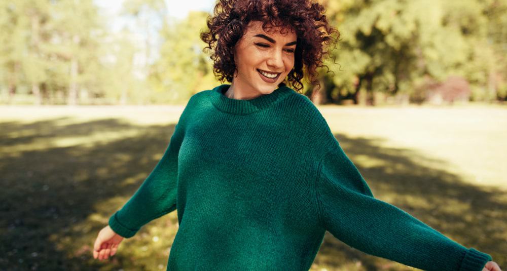 Carefree woman wearing a green set-in sleeve sweater.