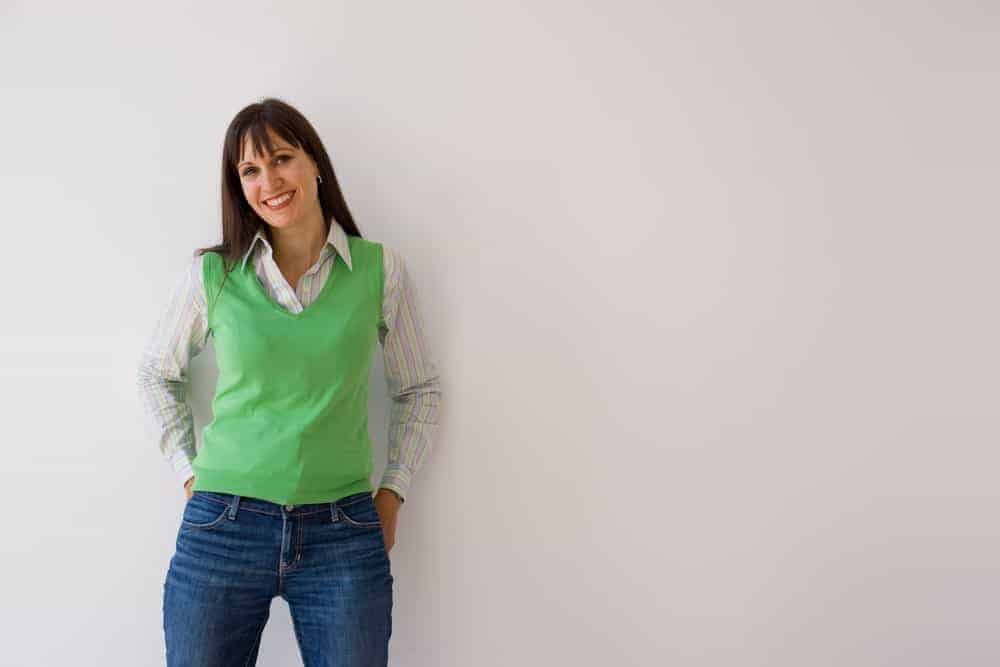 Woman in a long sleeve polo topped with a green vest sweater.