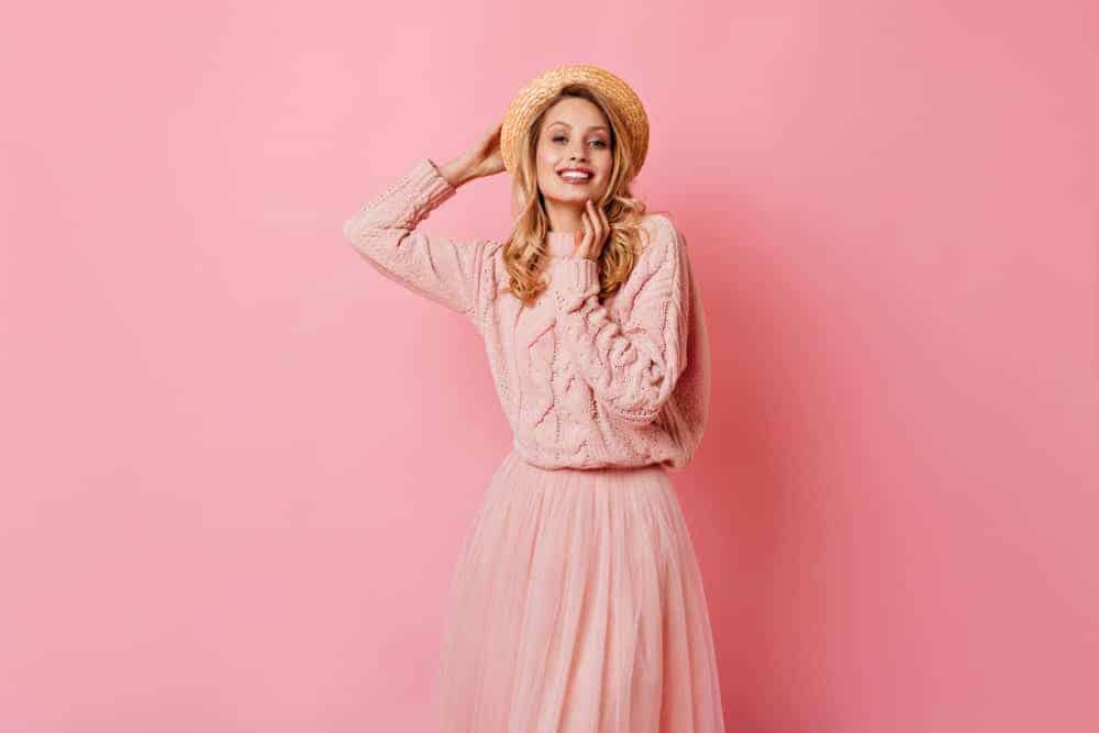 Woman in pink sweater dress blending on its background.