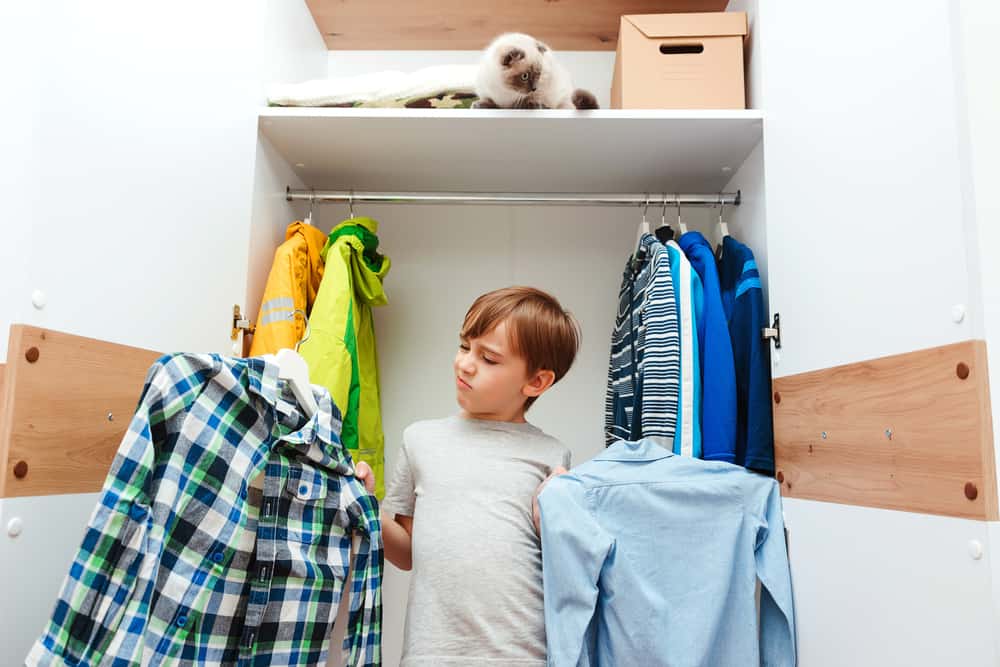 Young boy chooses clothes in the wardrobe closet.