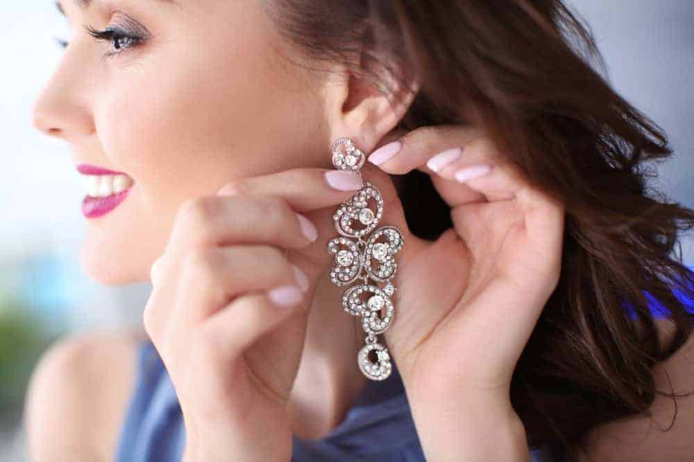 A woman putting on an earring on her left ear.