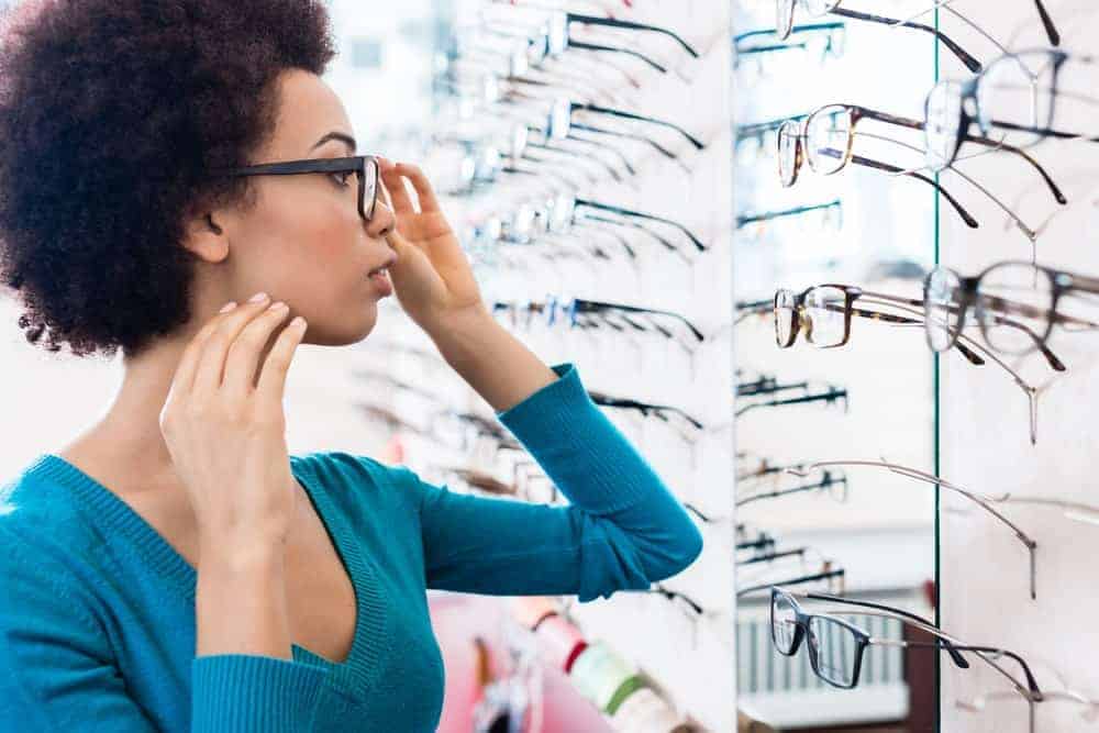 A woman browsing through various eyeglasses on display.