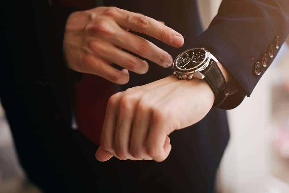 A close look at a man's watch and its black watchband.