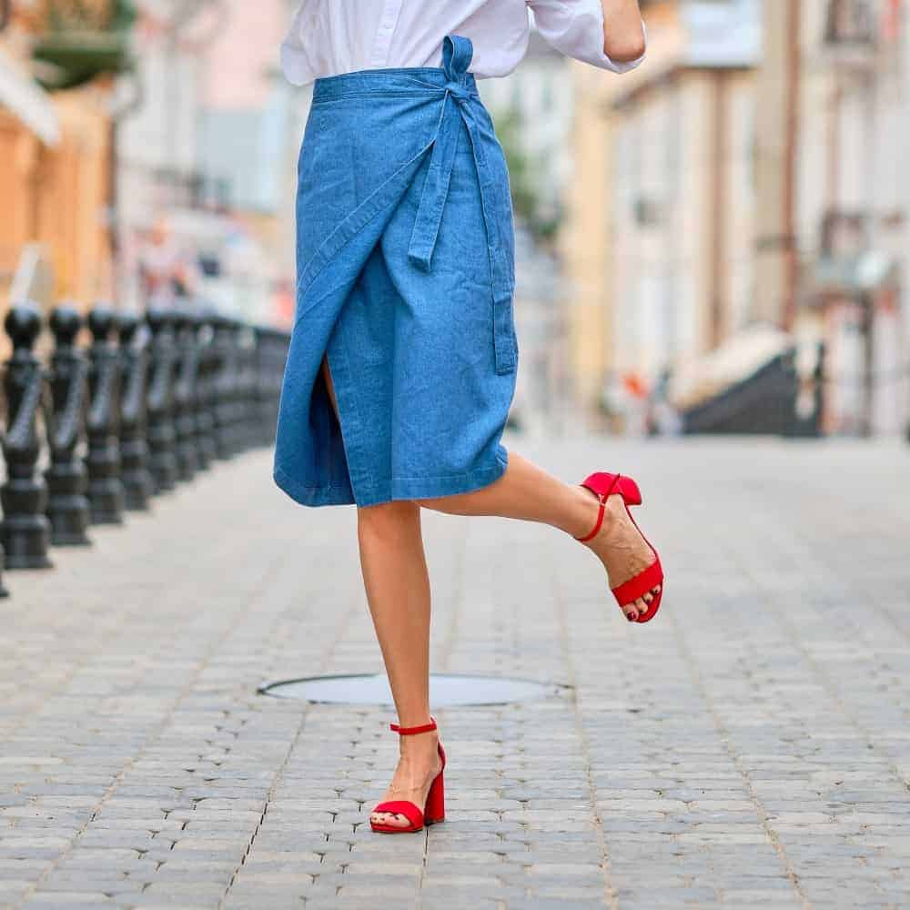 Woman wearing a blue wrap skirt and a pair of red heels.