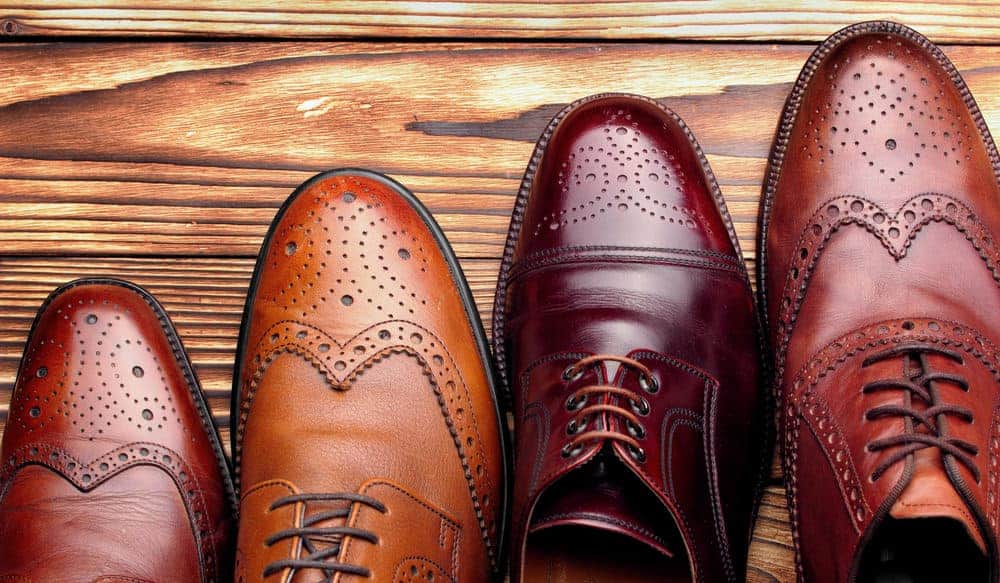 A variety of formal dress shoes on a wooden surface.