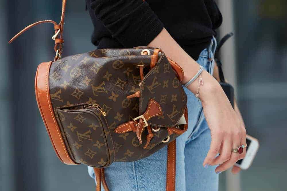 A close look at a woman carrying a Louis Vuitton backpack.
