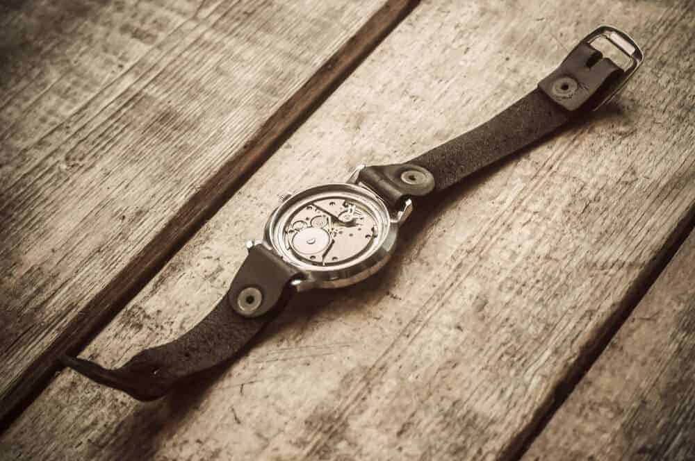 A broken wristwatch on a wooden background.