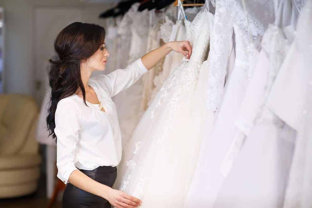 A woman browsing through the wedding dresses on display at a store.